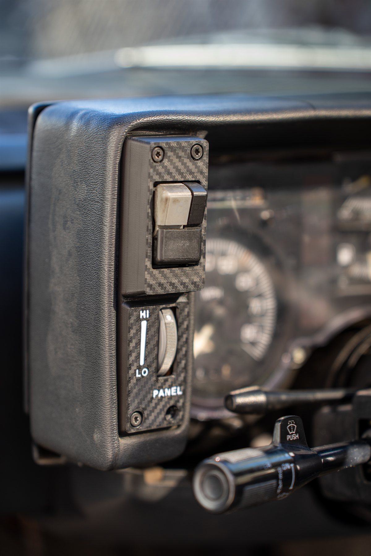 Reproduction Fiero driver-side cluster panel installed, close up of the headlight switch and dimmer with the HI, LO and PANEL legend inlaid in white