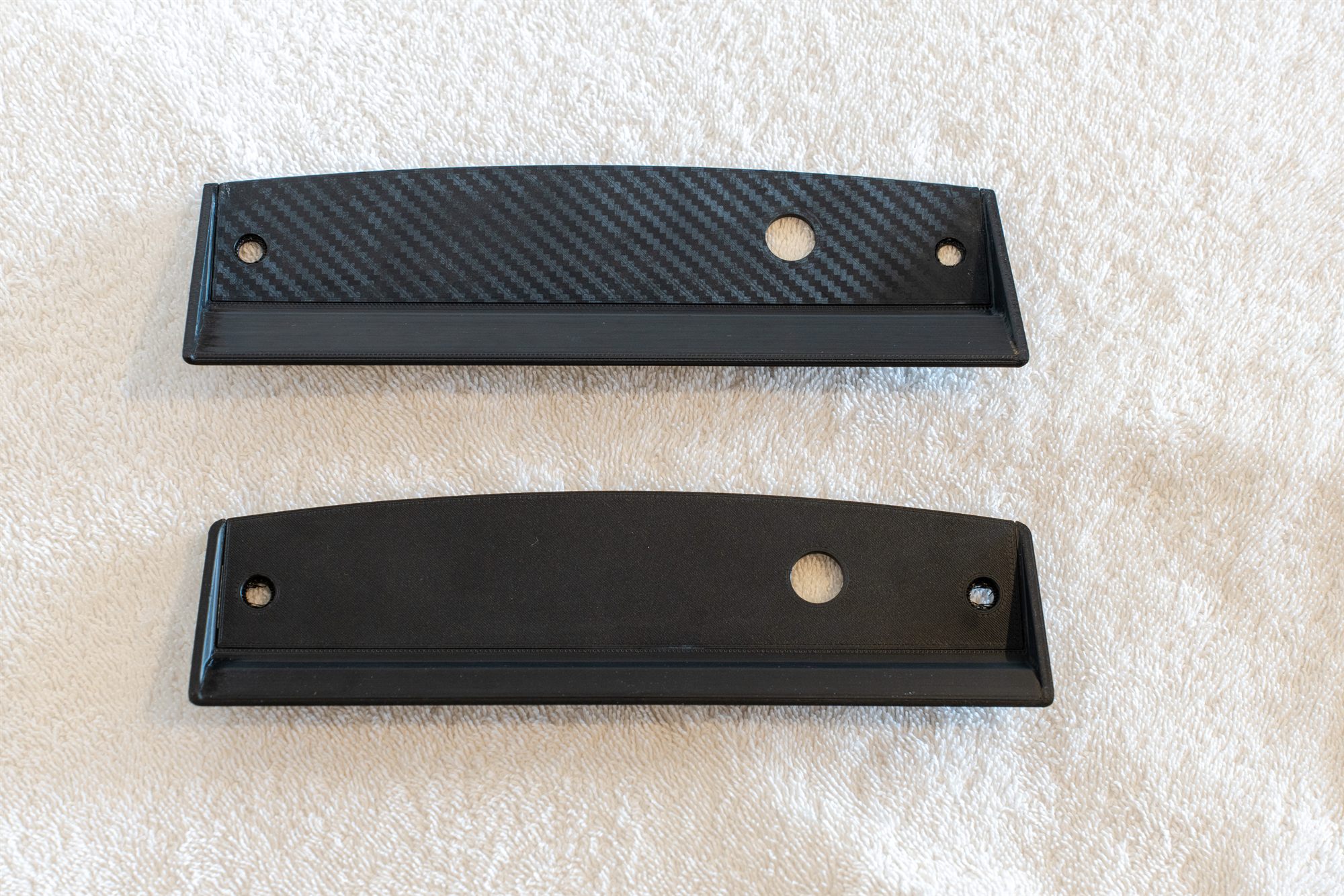 Reproduction Fiero cigarette lighter bezels in carbon weave and smooth finish, side by side